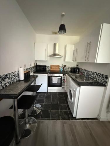 a kitchen with white cabinets and a table and a dishwasher at Stephen's Street Apartment, Inverness City Centre in Inverness