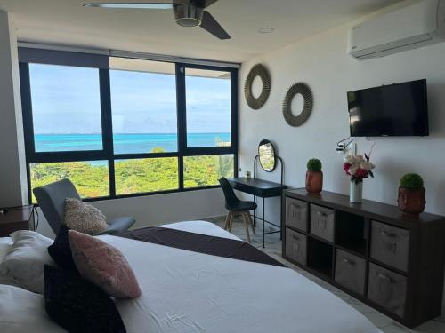 a bedroom with a bed and a desk with a television at Beautiful sea view apartment in the Hotel Zone Cancun in Cancún