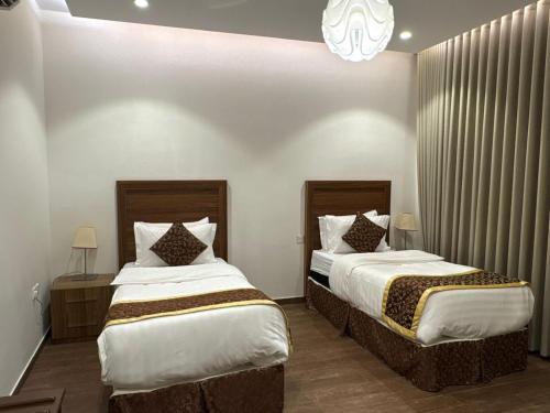 a bedroom with two beds and a chandelier at شقق سوار الذهب للشقق المخدومة in Sīdī Ḩamzah