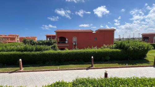 a red house in the middle of a garden at Caribiano villa-3 in Dawwār Ḩalīs