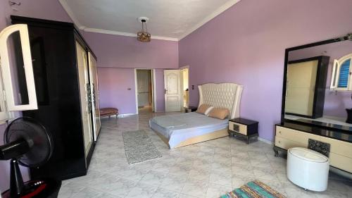 a bedroom with a bed and purple walls at Caribiano villa-3 in Dawwār Ḩalīs