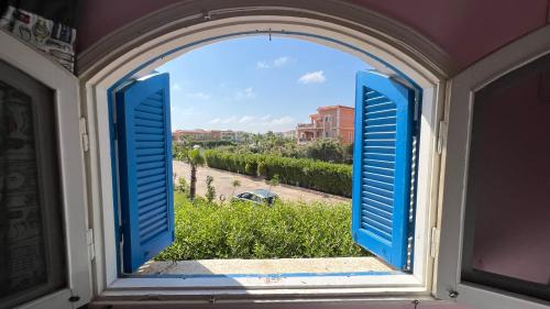 an open window with blue shutters and a view at Caribiano villa-3 in Dawwār Ḩalīs