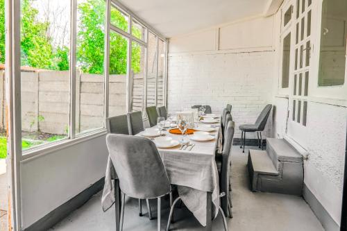 a dining room with a table and chairs and windows at Family 4-Bed Wembley Stadium Home - Parking & Long Stays in London