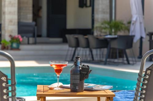 a bottle of wine and a glass on a table by a pool at Villa PERLA VERDE in Labin