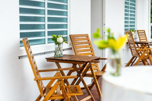 a table and chairs on a porch with a vase of flowers at Coconut Palms Inn in Rincon
