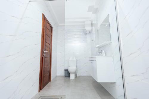 a white bathroom with a toilet and a sink at BM Properties in Accra