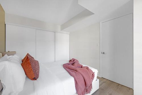 a bedroom with white walls and a bed with a pink blanket at Luxury Waterfront Escape Stylish 3BR Condo in Toronto