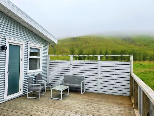 a deck with two chairs and a bench on a house at Seljanlandsfoss Sky Retreat in Hvolsvöllur