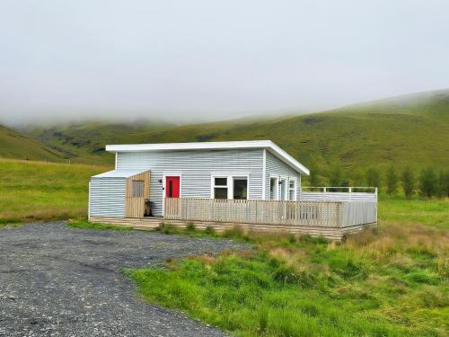 a small house with a red door in a field at Seljanlandsfoss Sky Retreat in Hvolsvöllur