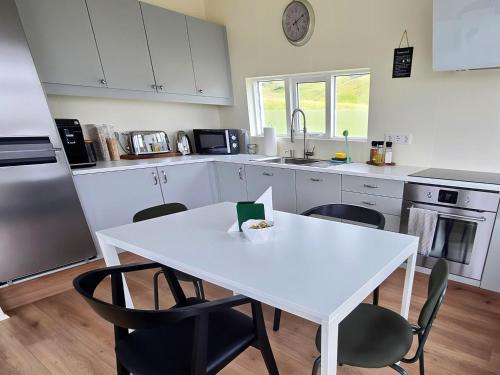 a kitchen with a white table and chairs at Seljanlandsfoss Sky Retreat in Hvolsvöllur