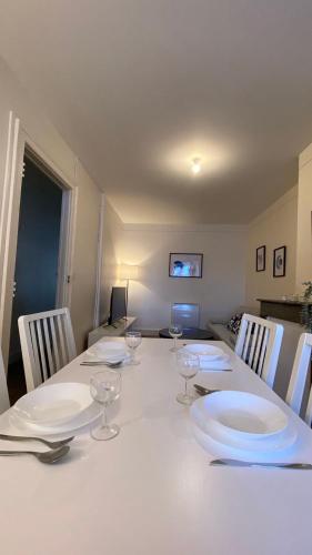 a white table with plates and wine glasses on it at Le Béarnois - 3 Chambres - Myra Conciergerie in Pau