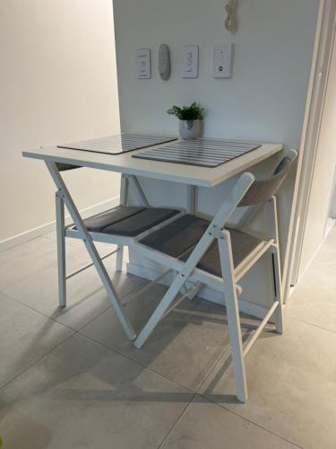 a white table and a chair with a plant on it at Coastline Escape Renovated Unit - Great Location - Quiet Area - Parking Included in Gold Coast