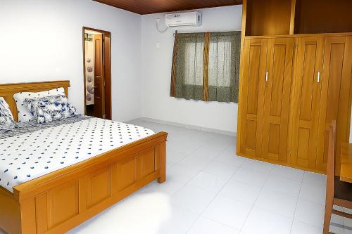 a bedroom with a wooden bed and wooden cabinets at La Maison Du Voyageur in Kribi