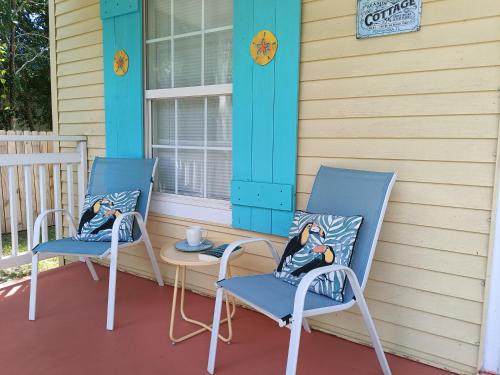 two chairs and a table on the front porch of a house at Pensacola hidden gem cottage 3 minutes from Navy Base, pet friendly in Pensacola