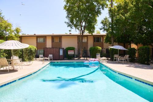 a swimming pool with chairs and umbrellas in front of a building at The Scott Getaway - Walkable to Old Town, remodeled space, outdoor pool! in Scottsdale