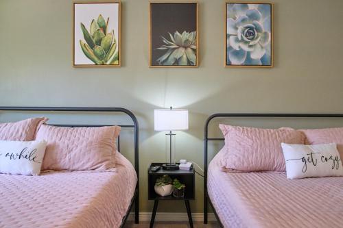 two beds in a bedroom with pink sheets and pillows at The Scott Getaway - Walkable to Old Town, remodeled space, outdoor pool! in Scottsdale