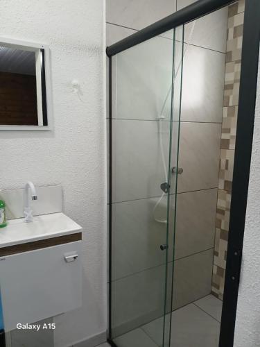 a shower with a glass door next to a sink at Vilamar in Florianópolis