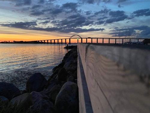a bridge over a body of water at sunset at 4 person holiday home in Rudkøbing-By Traum in Rudkøbing