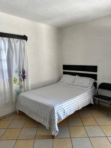 a bed in a room with a window and a chair at Rincon el Mirador in Tamasopo