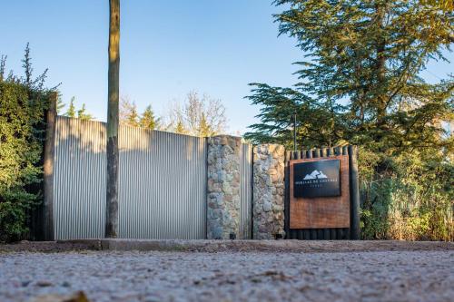 a fence with a stone wall and a sign at Huellas de Chacras in Ciudad Lujan de Cuyo