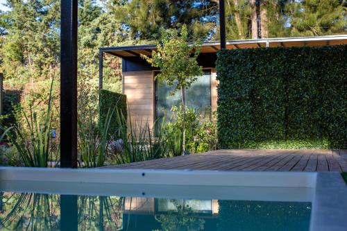 a house with a wooden deck next to a hedge at Huellas de Chacras in Ciudad Lujan de Cuyo