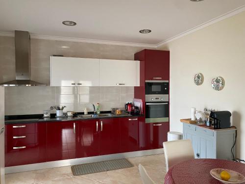 - une cuisine avec des placards rouges et une table dans l'établissement Chez Ilda - Casa da Ilda Alojamento Local, à Folhadal