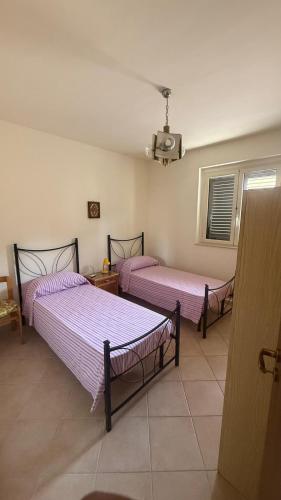two beds in a room with purple sheets at PM 56 Via Grande in Realmonte