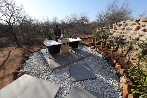 a man is standing next to a garden with rocks at Oase by 7 Star Lodges - Greater Kruger Private 530ha Reserve in Hoedspruit