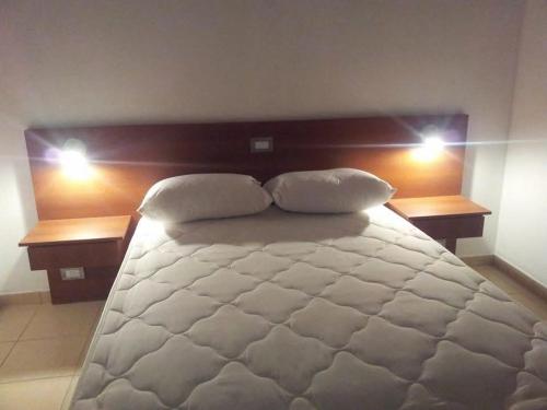 Un dormitorio con una gran cama blanca con dos almohadas. en El Cacique, en General San MartÃ­n