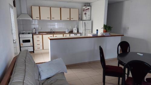 Una sala de estar con un sofá y una mesa y una cocina. en El Cacique, en General San MartÃ­n