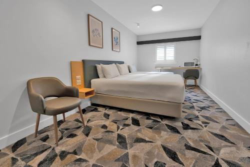 a bedroom with a bed and a chair and a desk at The Palmer Collective in Townsville