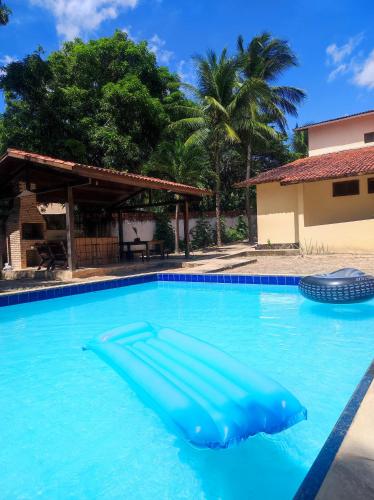 a swimming pool with a blue raft in the water at Maison Tropical in Paracuru