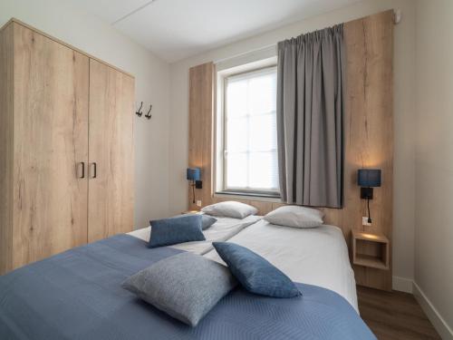 a bedroom with two beds with blue pillows at SeaLuxe Residence in Colijnsplaat
