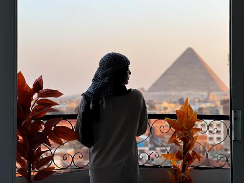 a woman looking out of a window at the pyramids at three pyramids view & jacuzii in Cairo