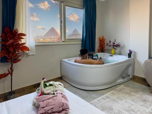a man in a bath tub in a bathroom with pyramids at three pyramids view & jacuzii in Cairo