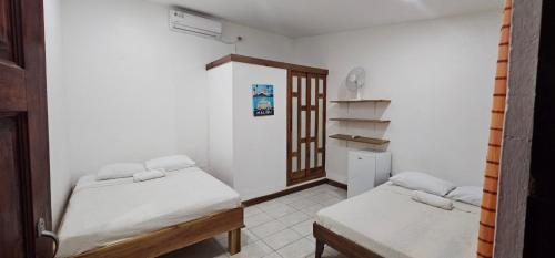 a small room with two beds and a closet at Santa Toro Inn in Santa Teresa Beach