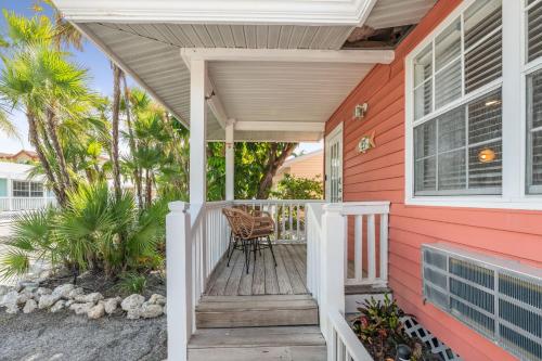 a front porch of a red house with a chair on it at Barefoot Boho- Beach bungalow on Anna Maria Island in Bradenton Beach