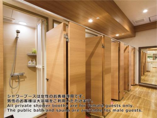 a shower stall with glass doors in a bathroom at Shinjuku Kuyakusho-mae Capsule Hotel in Tokyo