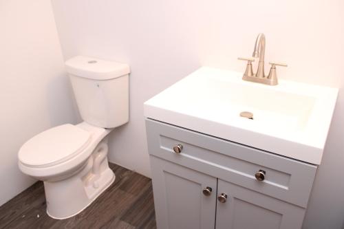 a white bathroom with a toilet and a sink at Roseld court in Oxon Hill