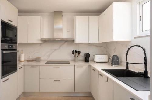 eine weiße Küche mit weißen Schränken und einer Spüle in der Unterkunft RETIRO Da CALHETA in Estreito da Calheta