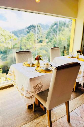 a table with a white table cloth and chairs and a window at Pousada Valle do Sol in Campos do Jordão