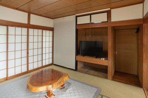 a living room with a table and a tv at Tokiwaya in Kusatsu