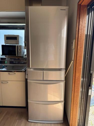 a stainless steel refrigerator in a kitchen with a microwave at Tokiwaya in Kusatsu