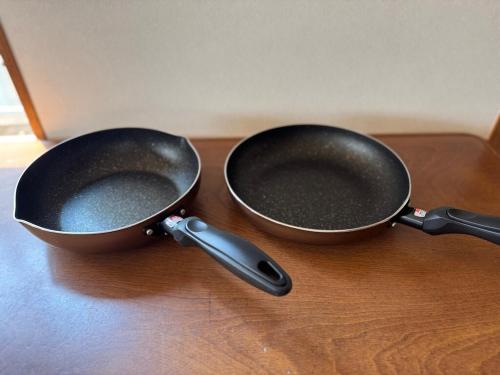 two frying pans sitting on a wooden table at Tokiwaya in Kusatsu