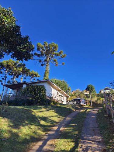 a house with a tree on the side of a road at Chalés Valle do Sol in Campos do Jordão
