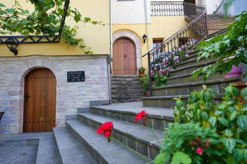 a building with two doors and stairs with red flowers at Palorto Traditional Hotel in Gjirokastër