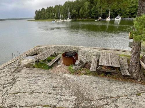 a picnic table and bench next to a body of water at 2 person holiday home in FäRENTUNA in Kungsberga