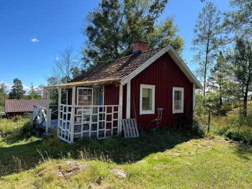 a small red house with a porch in a field at 2 person holiday home in FäRENTUNA in Kungsberga