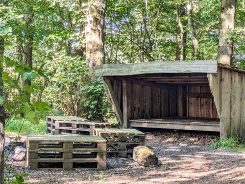a wooden shelter with benches in the woods at 6 person holiday home in Gram in Gram