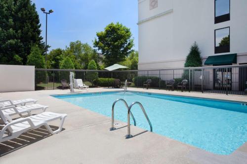 una piscina con sedie a sdraio e un edificio di Wingate by Wyndham Garner/Raleigh South a Garner